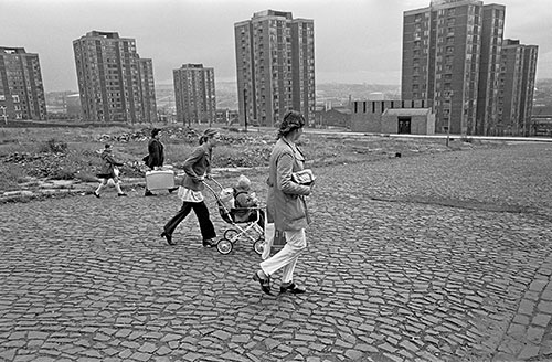Family crossing slum cleared land by tower blocks, Newcastle  (1975)