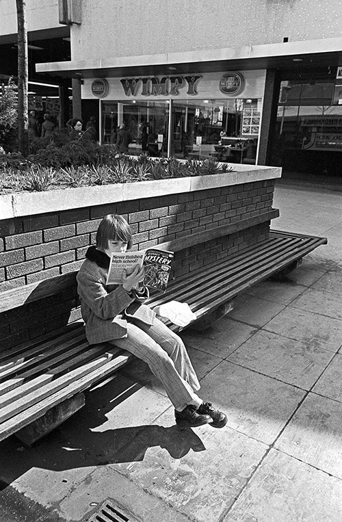 Teenager reading 'Journey into Mystery' in a shopping precinct Wolverhampton (1975)